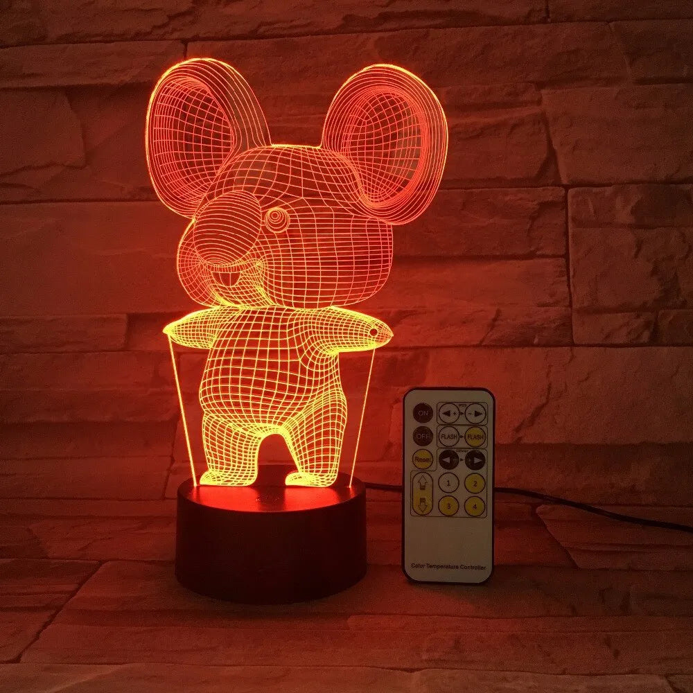 Black koala-shaped LED night light with remote control on a table, showing multi-colour illumination.