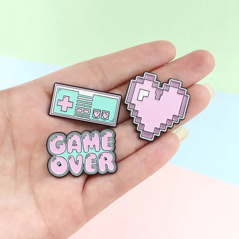 Stereo game console badge pin made from alloy metal on a bag, showing three colour variant options.