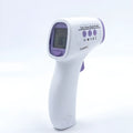White digital thermometer for non-contact temperature measurement on a table.