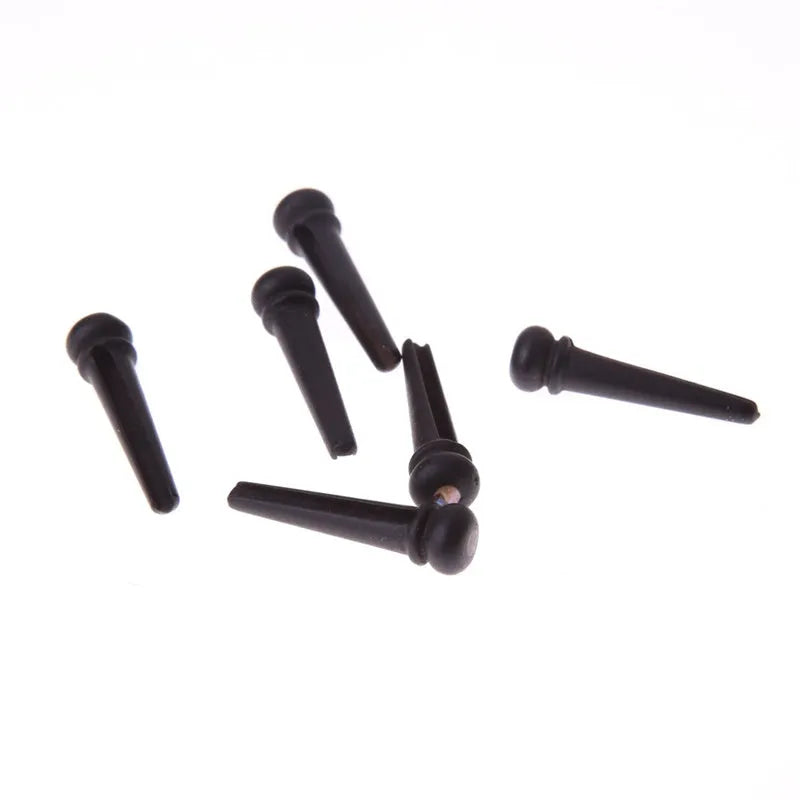 Six ebony guitar bridge pins with matt black finish on dark surface