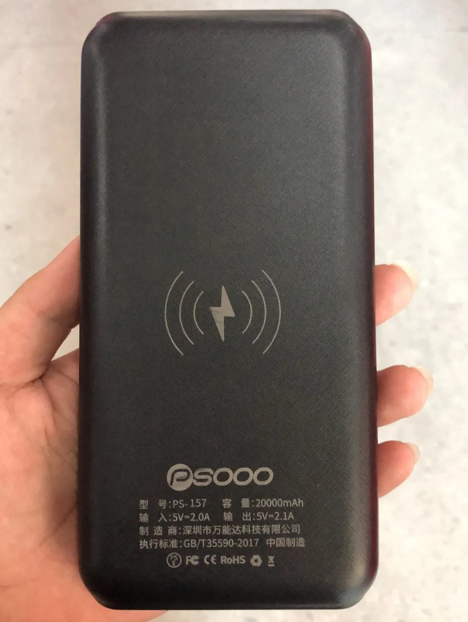 Black portable power bank with wireless charging surface and three USB ports for multiple device charging