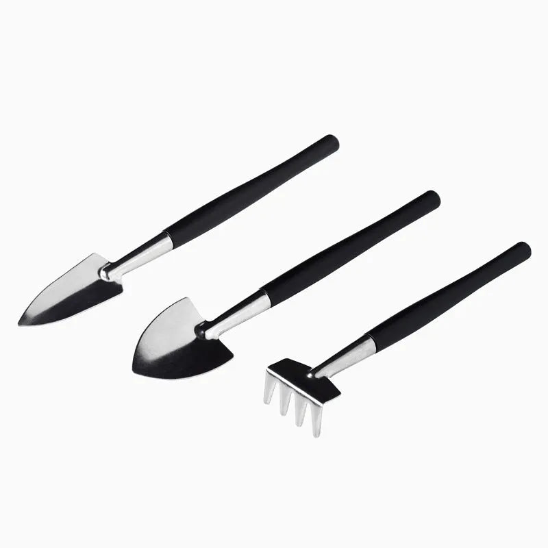 Black plastic and metal succulent plant tool set with 16 pieces including tweezers, shovel, and watering bottle on a grey cushion.