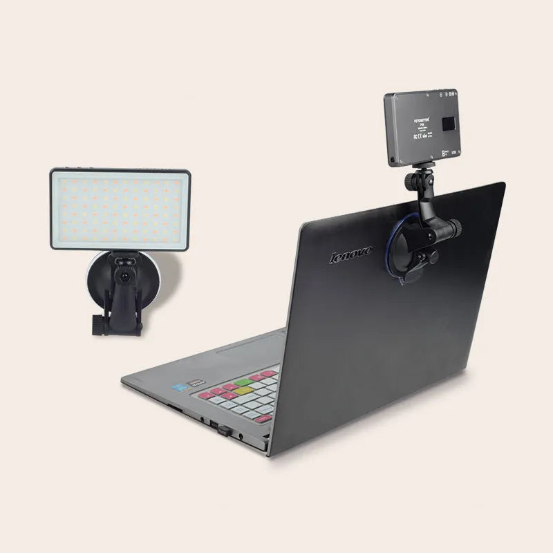 Black aluminium LED video light panel with clip mount, shown illuminating a person on a laptop video call.