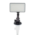 Black aluminium LED video light panel with clip mount, shown illuminating a person on a laptop video call.