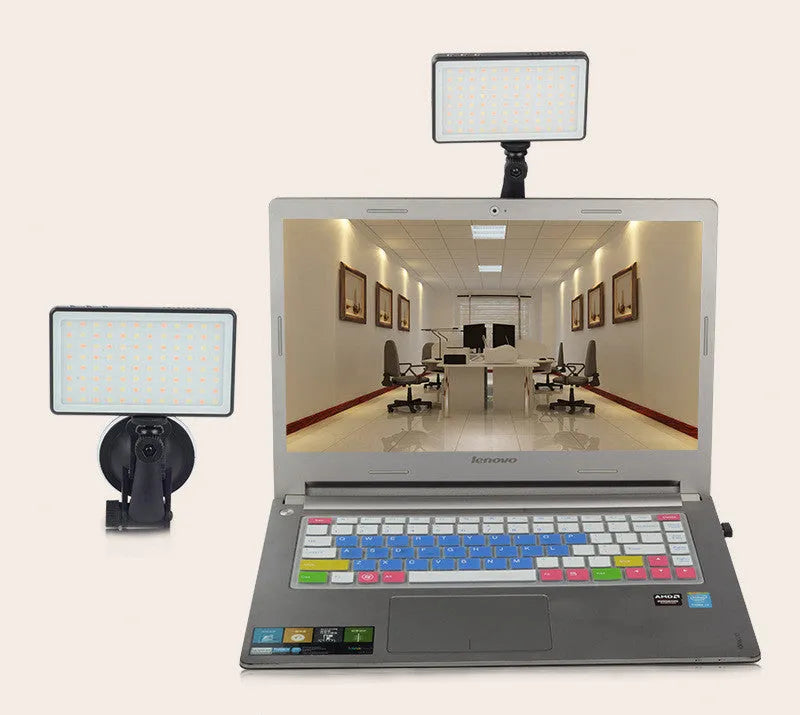 Black aluminium LED video light panel with clip mount, shown illuminating a person on a laptop video call.