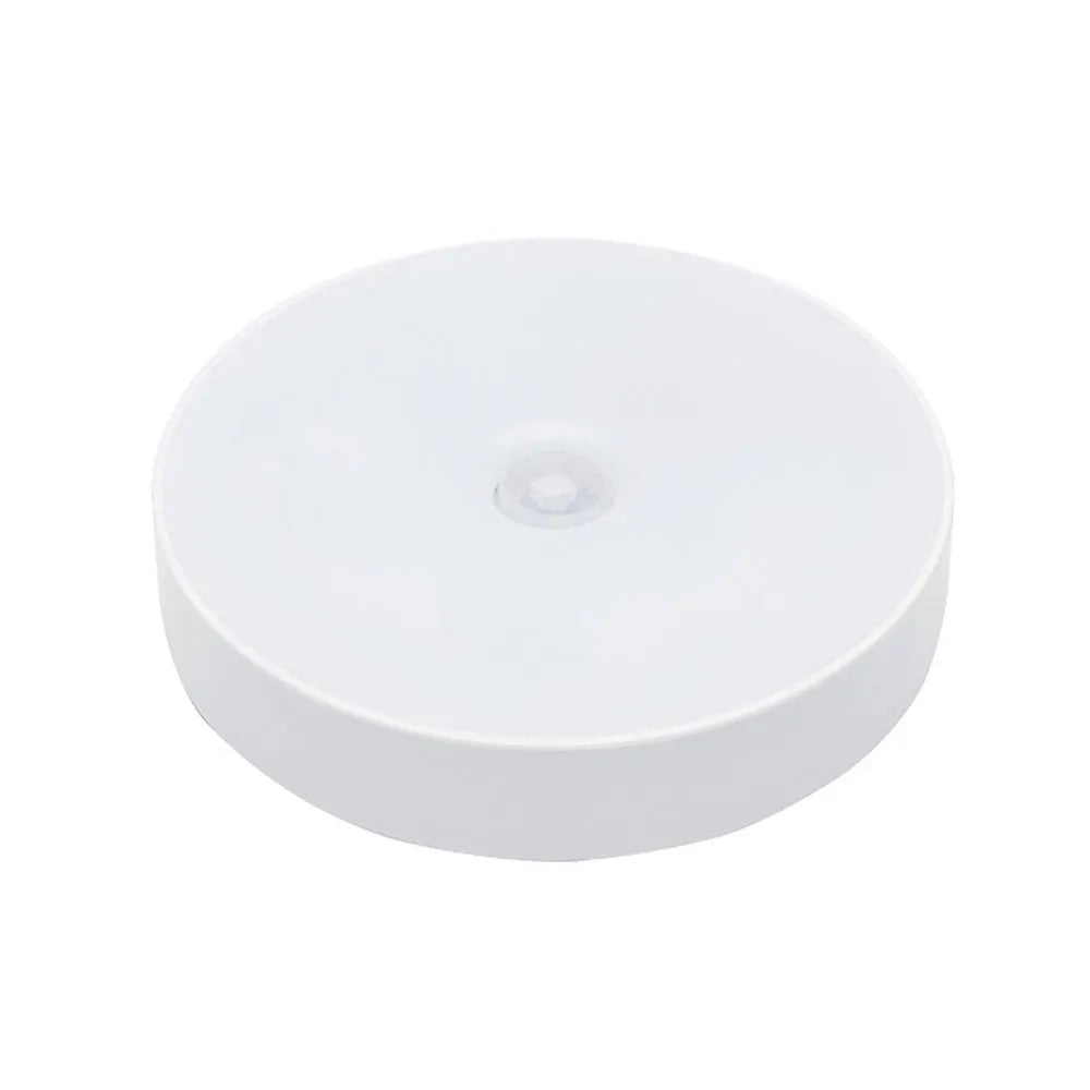 Small white circular USB rechargeable motion sensor LED night light with adhesive backing.