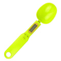 Black electronic measuring spoon scale showing digital display, placed on a kitchen counter.