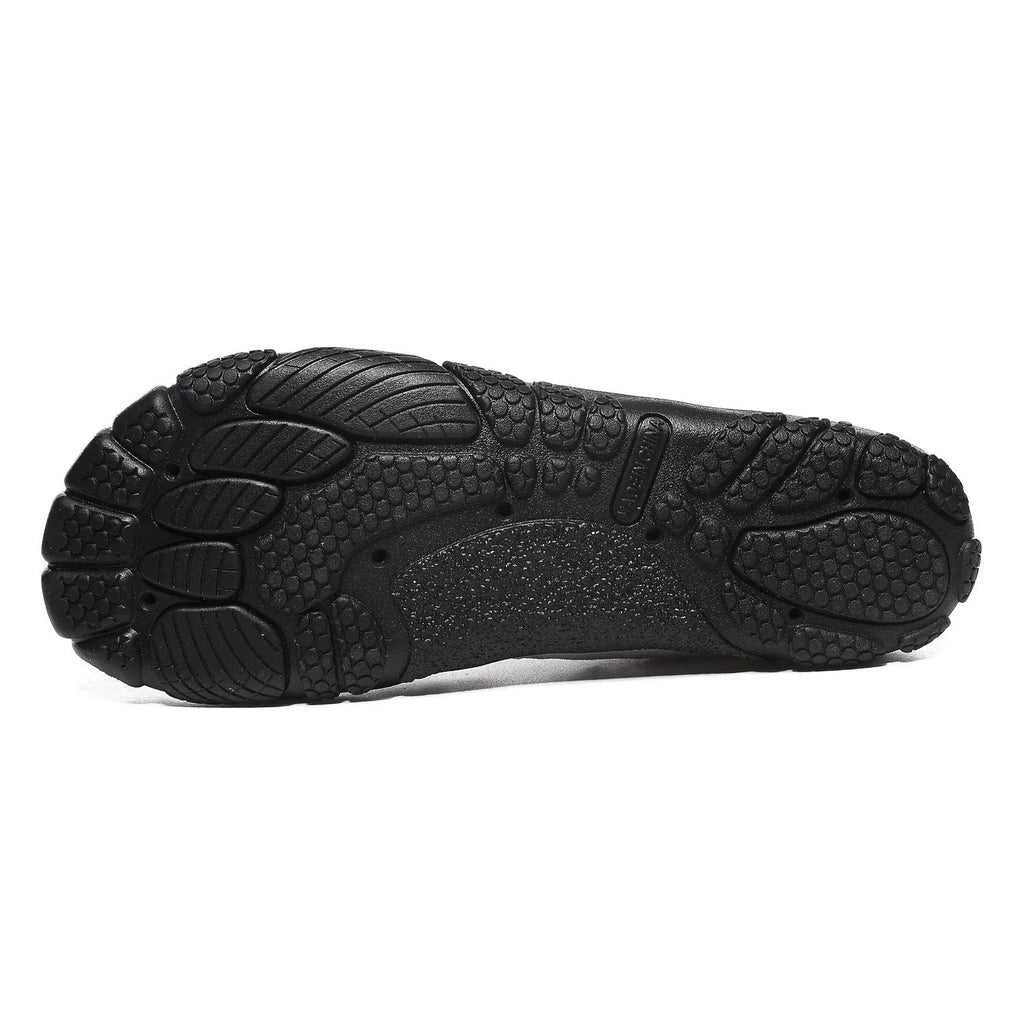 Unisex black quick-dry water shoes with mesh upper and elastic band, shown on a rocky riverbank.