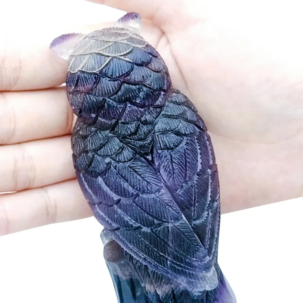 Hand carved purple fluorite owl ornament on a neutral background, showing detailed carving and natural crystal colour.