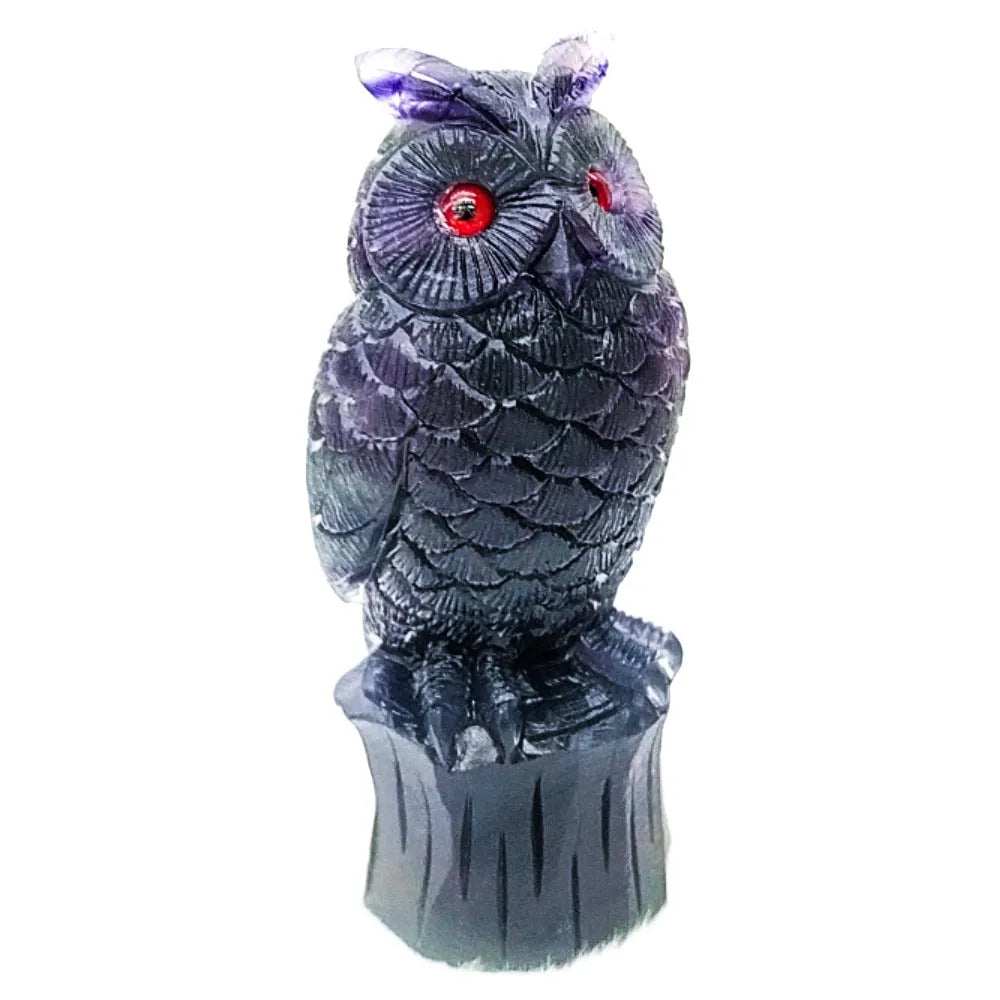 Hand carved purple fluorite owl ornament on a neutral background, showing detailed carving and natural crystal colour.