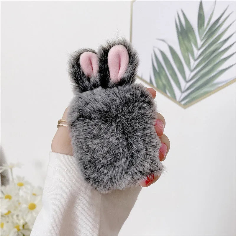 Pink silicone AirPods case with grey plush rabbit ears charm on Apple AirPods charging case