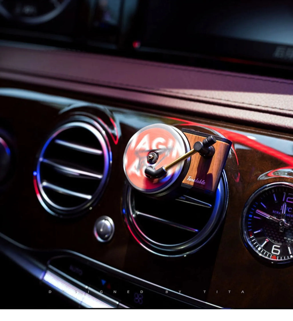 Brown alloy solid car perfume with record locomotive design clipped to a car air vent.