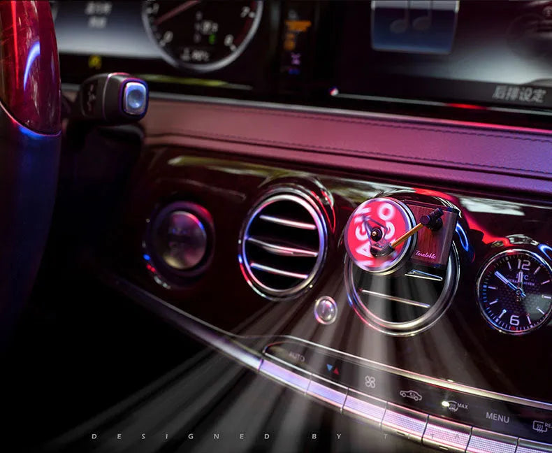 Brown alloy solid car perfume with record locomotive design clipped to a car air vent.