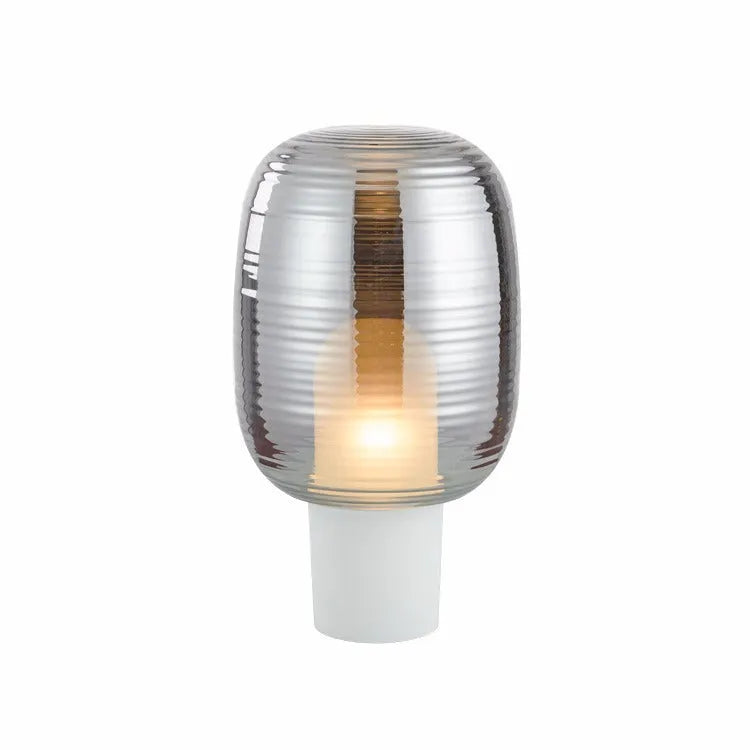 Simple modern glass table lamp in cognac colour on a wooden table.