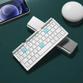 Silver white folding Bluetooth keyboard with built-in stand holding a tablet