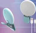 Small round white clip-on LED fill light attached to a mobile phone for selfies.