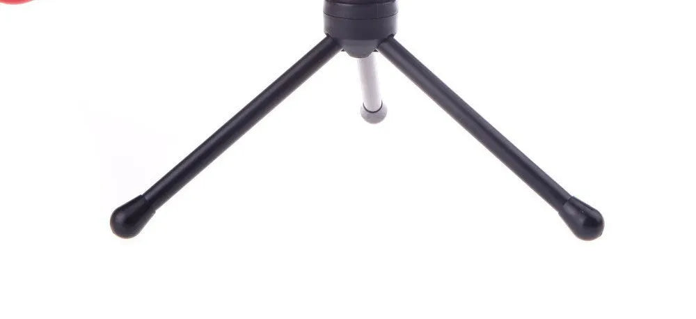 Black wired PC microphone with a clip holder on a desk next to a computer.