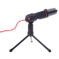 Black wired PC microphone with a clip holder on a desk next to a computer.