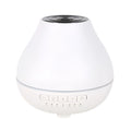 White circular Bluetooth humidifier and aroma diffuser with night light on a table.