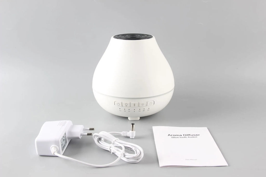 White circular Bluetooth humidifier and aroma diffuser with night light on a table.
