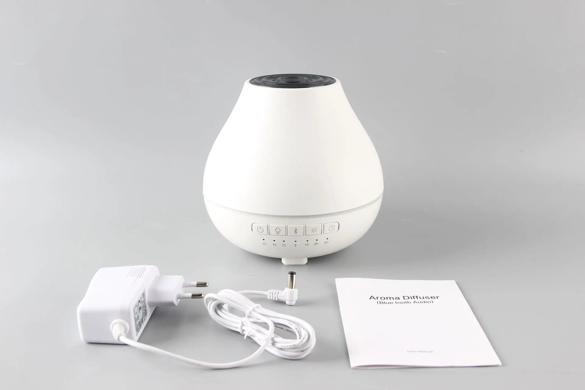 White circular Bluetooth humidifier and aroma diffuser with night light on a table.