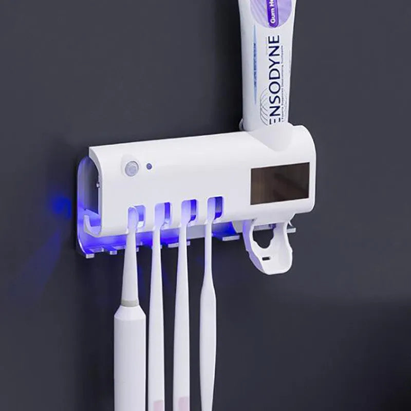 White automatic toothpaste squeezer and toothbrush steriliser unit mounted on bathroom wall