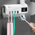 White automatic toothpaste squeezer and toothbrush steriliser unit mounted on bathroom wall