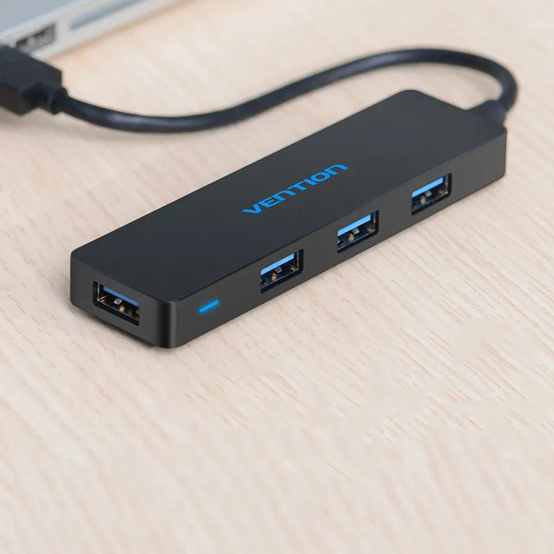 Black USB 3.0 hub with four ports, short attached cable, and nickel-plated connectors.