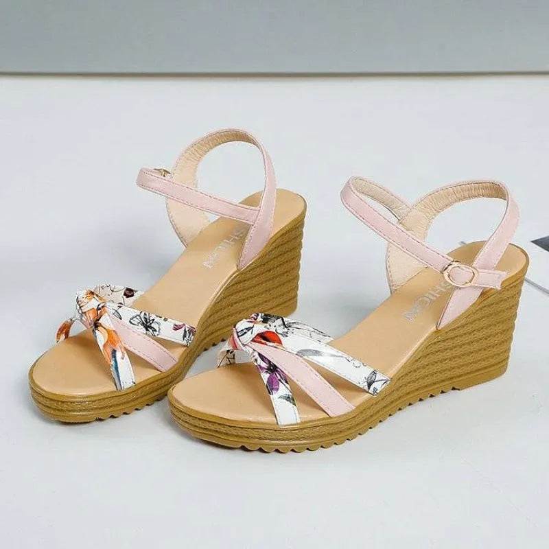 Pink women's wedge sandals with a thick heel, fish mouth design, and a silver buckle.
