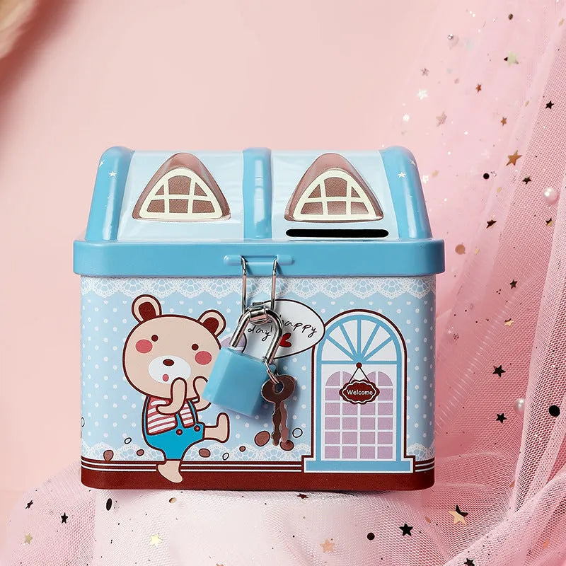 Blue house-shaped tinplate piggy bank with round coin slot on desktop.