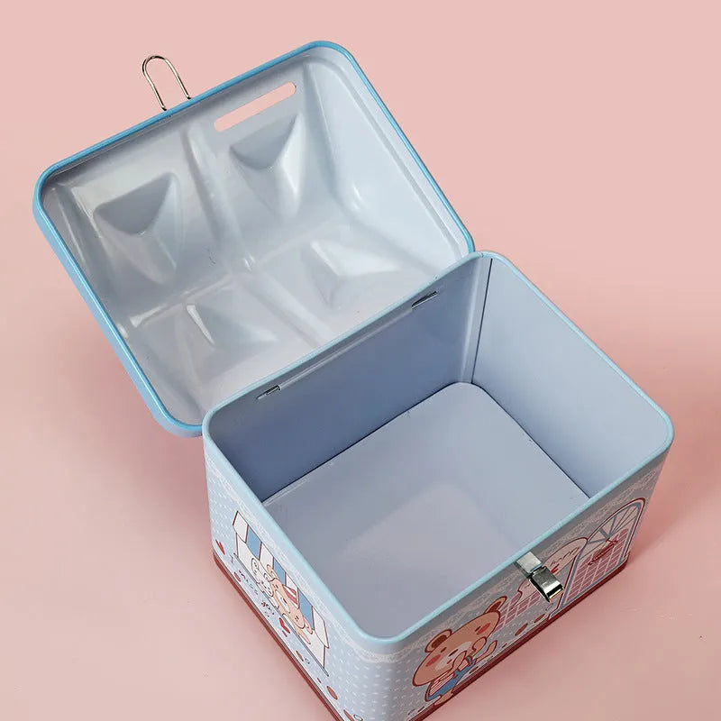 Blue house-shaped tinplate piggy bank with round coin slot on desktop.