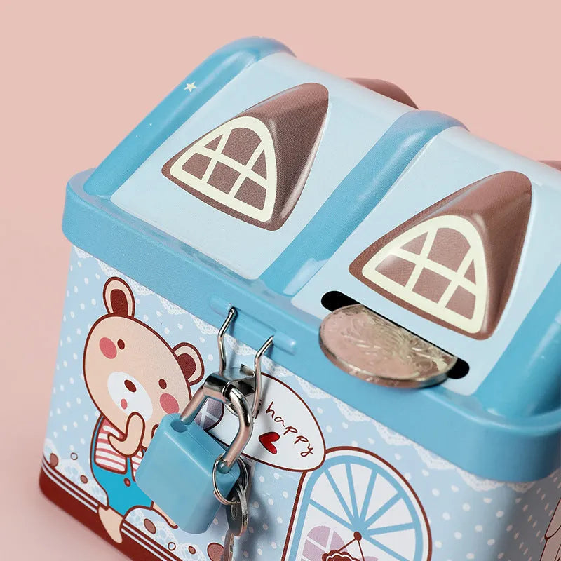 Blue house-shaped tinplate piggy bank with round coin slot on desktop.