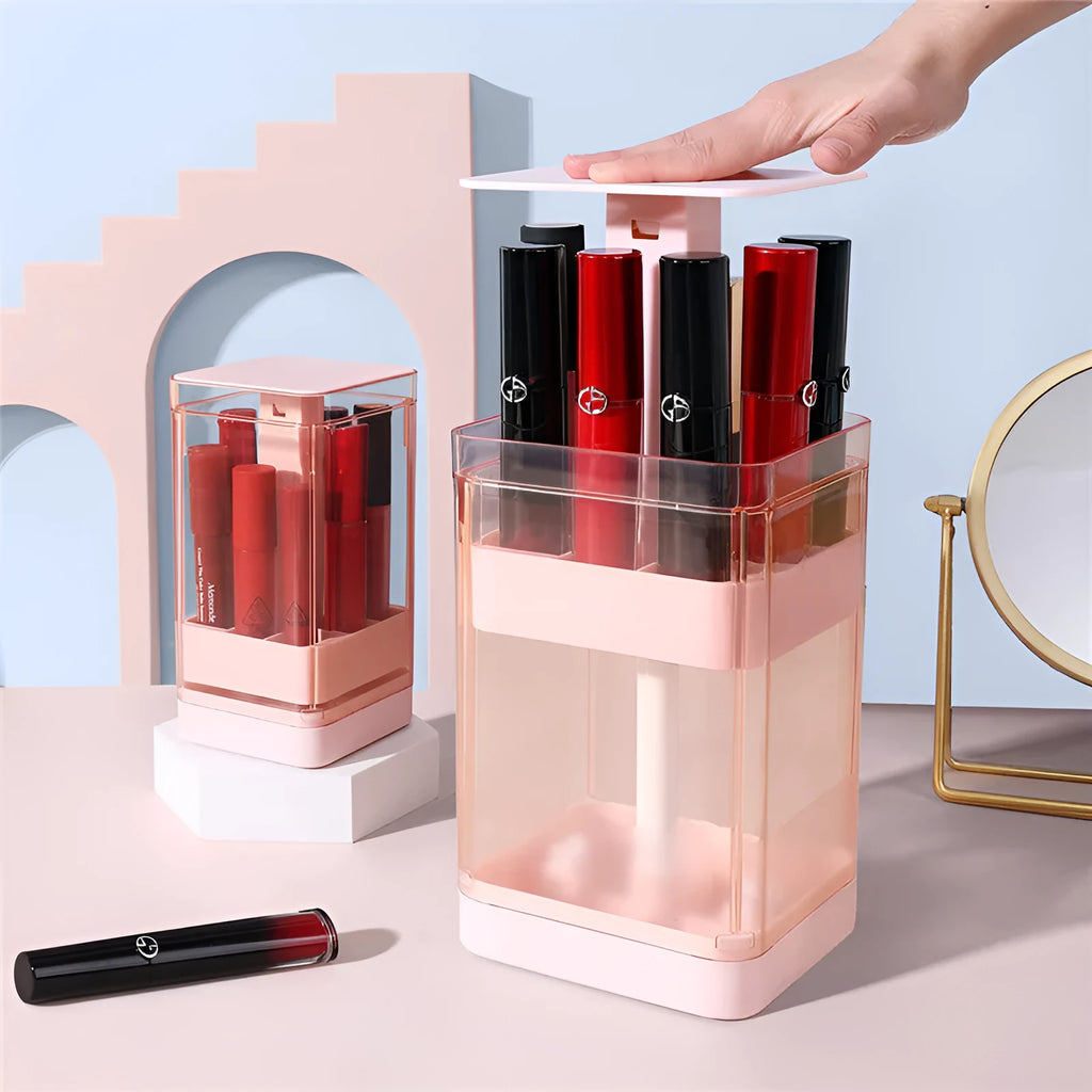 Clear press lift lipstick storage box with dust cover on a desktop, shown in pink and white.