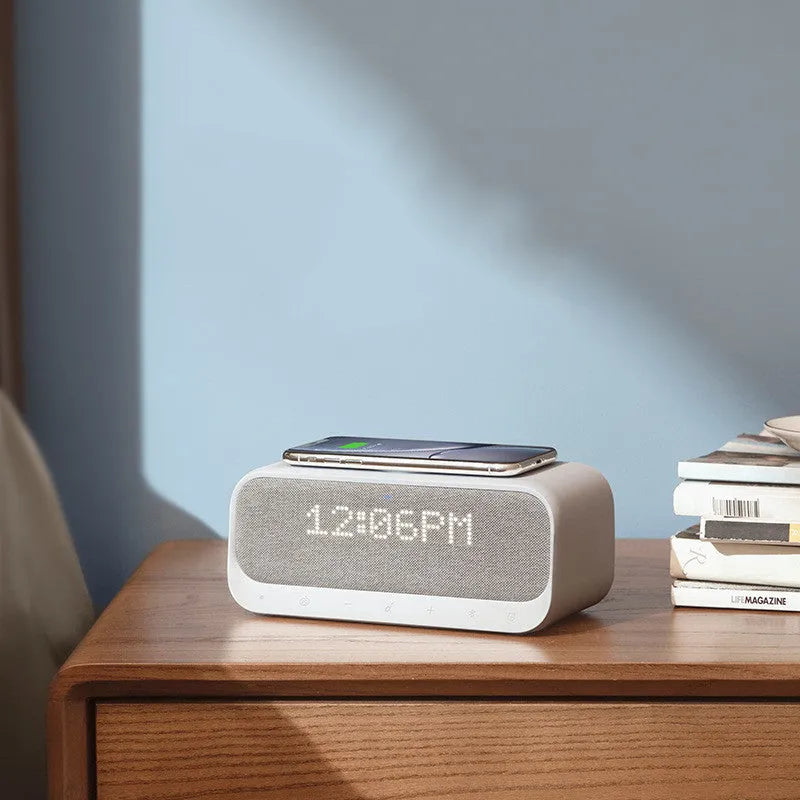 White Soundcore Bluetooth speaker with wireless charging top, digital display, and compact vertical design.