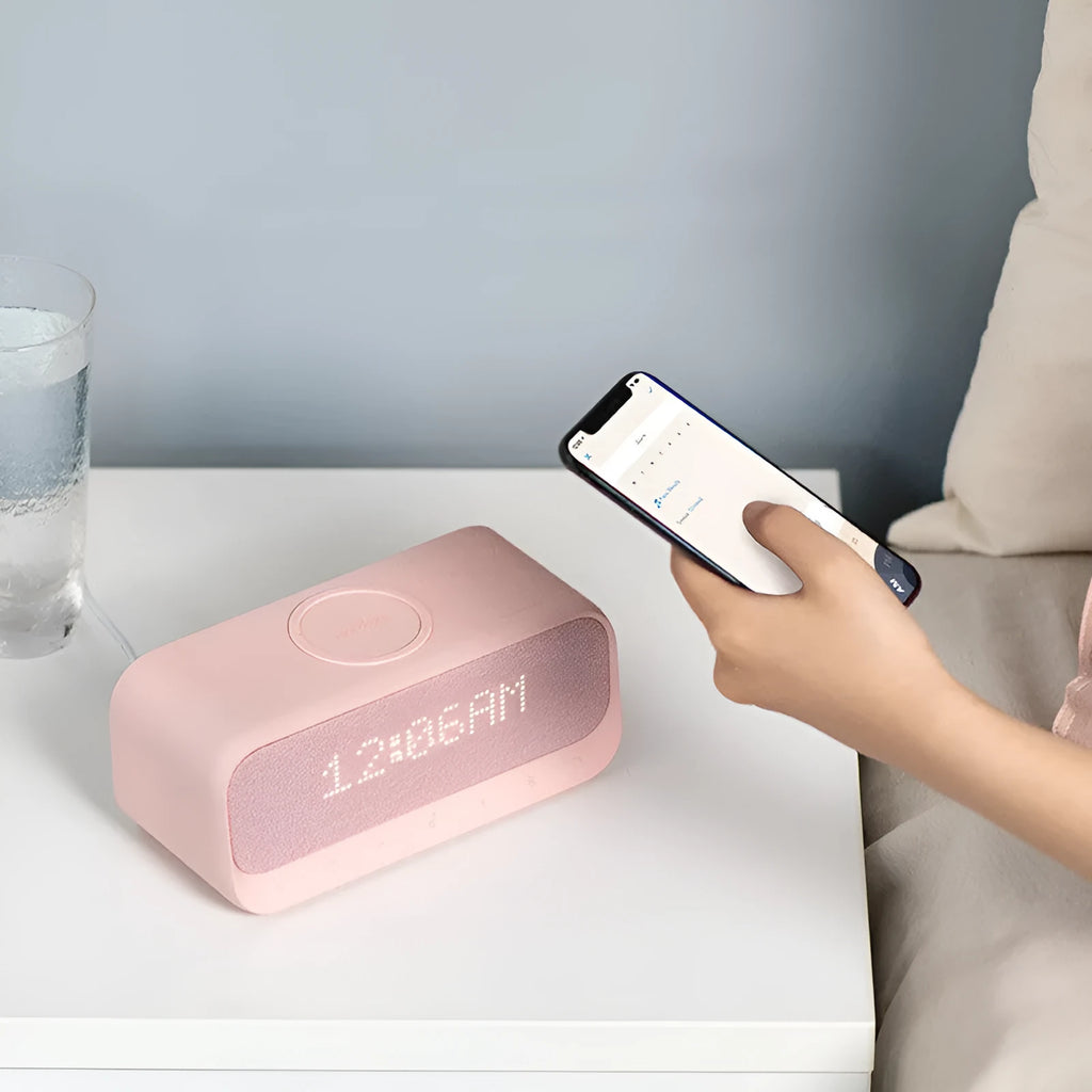 White Soundcore Bluetooth speaker with wireless charging top, digital display, and compact vertical design.