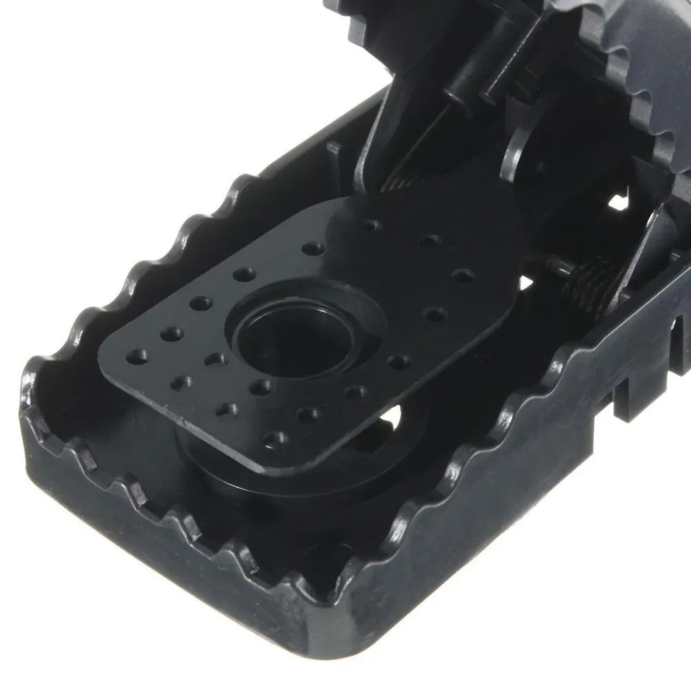 Six black plastic snapping mousetraps with set triggers on a white background.