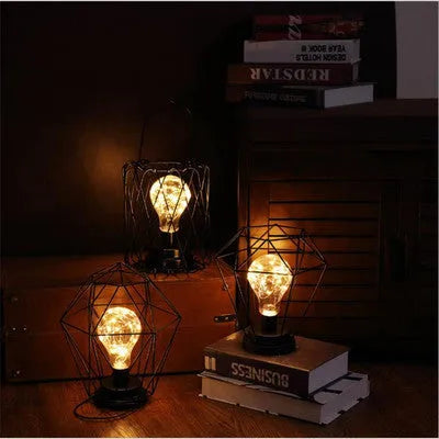 Minimalist hollow wrought iron table lamp in red wine bottle style on a wooden desk.