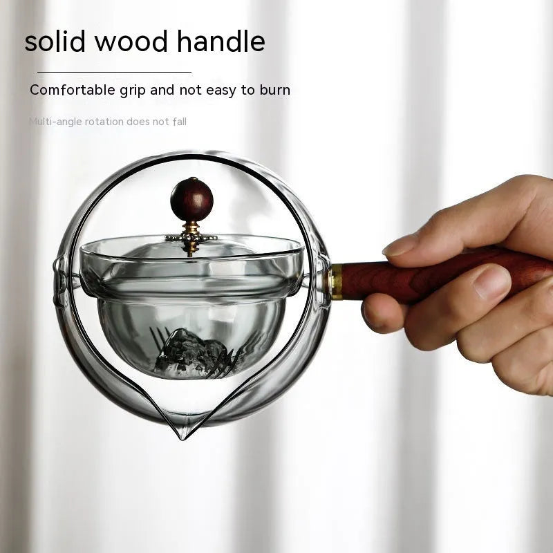 Semi-automatic rotary heat-resistant glass teapot with infuser and wooden handle on a table, transparent or grey