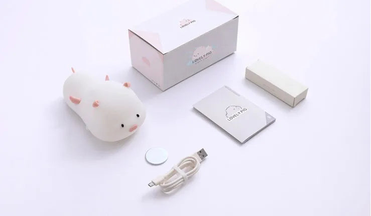 Cute pig silicone night light in Pink with sleeping face design on a wooden table