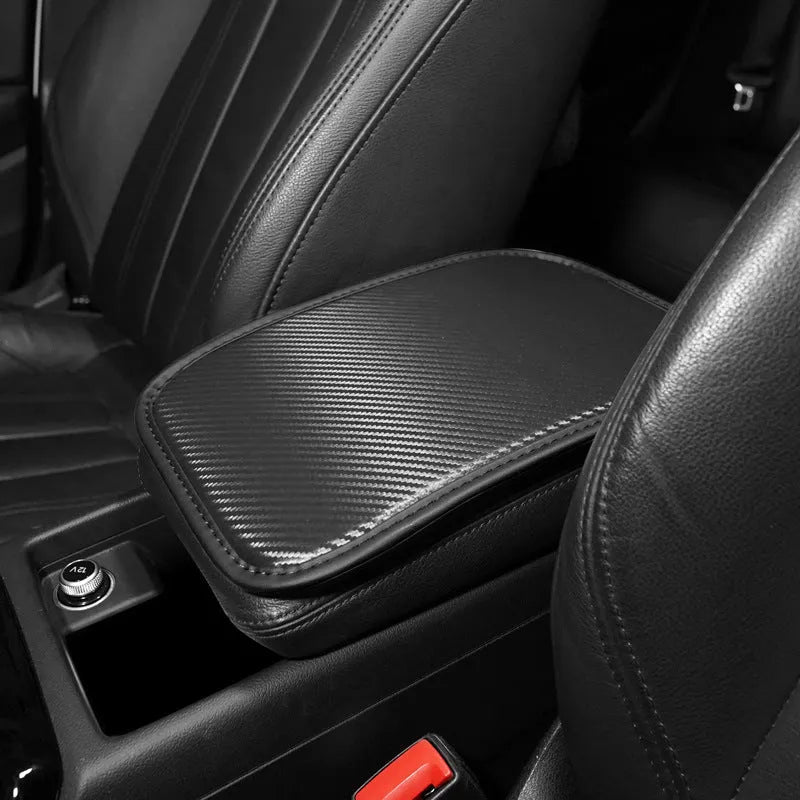Automotive carbon fibre armrest box mat in black leather, 29x19cm, on a car centre console