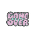 Stereo game console badge pin made from alloy metal on a bag, showing three colour variant options.