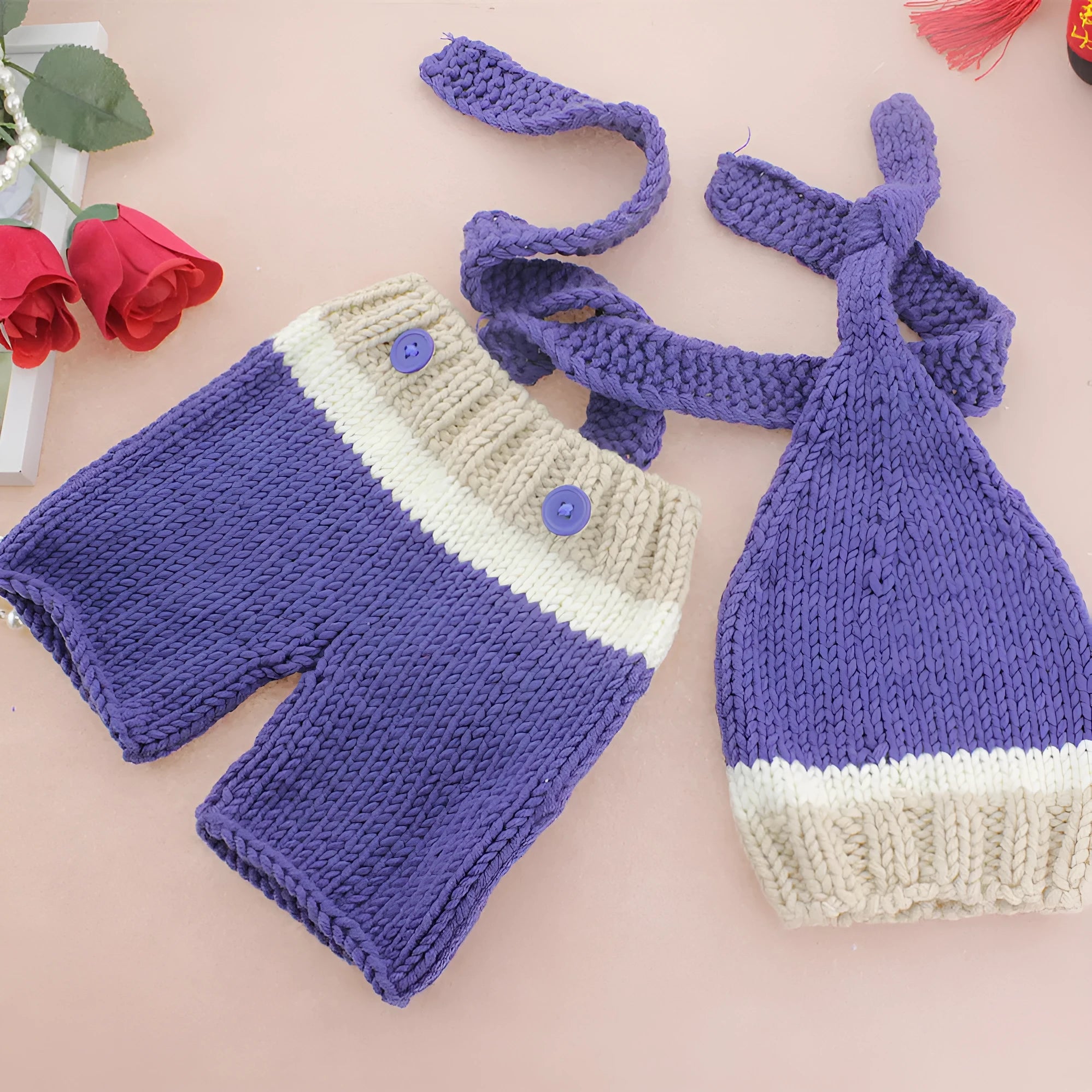 Handmade knitted wool baby photo suit in navy with hat and pants on a light background