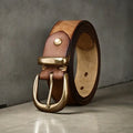 Men's brown genuine cowhide leather belt with a copper pin buckle on a jeans background.