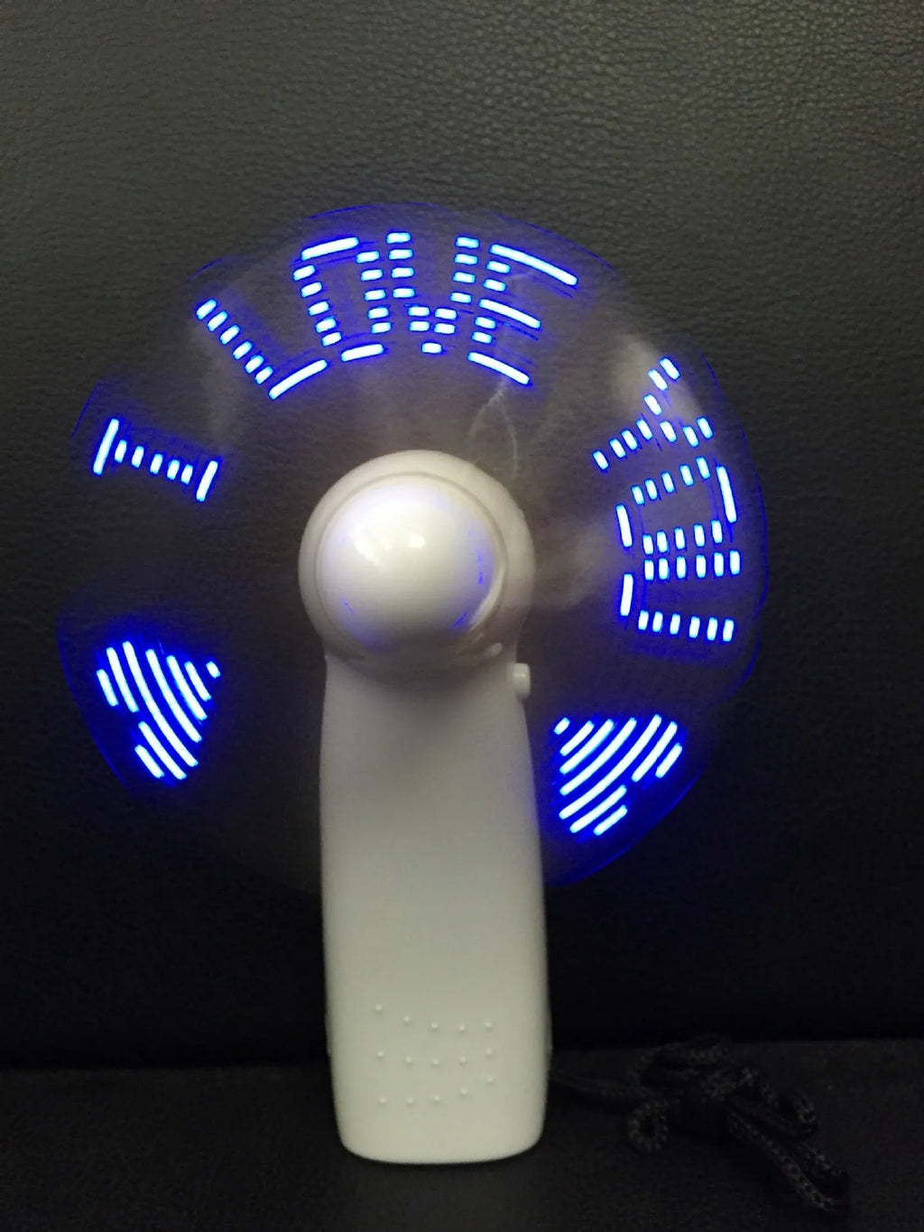 White handheld mini fan with LED love pattern lights flashing in blue and red colours
