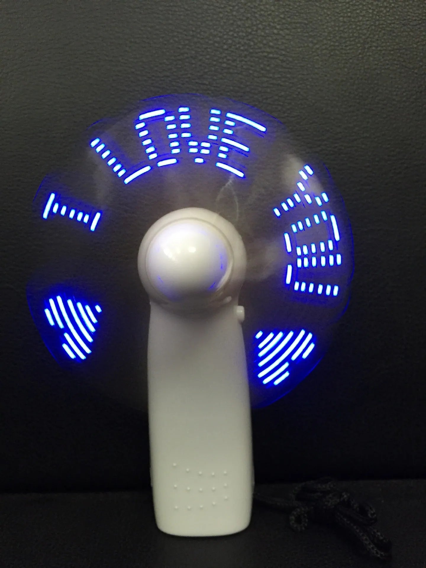 White handheld mini fan with LED love pattern lights flashing in blue and red colours