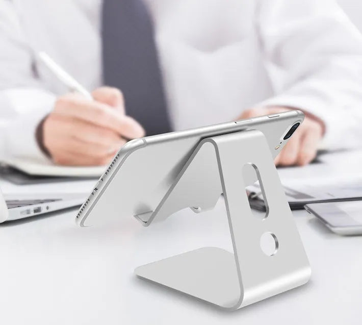 Aluminium alloy universal phone and tablet mount in silver colour on a wooden desk.