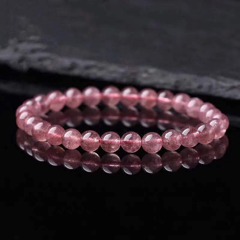 Women's bracelet with polished strawberry quartz crystal beads on an elastic cord, showing 6mm, 8mm and 10mm size options.