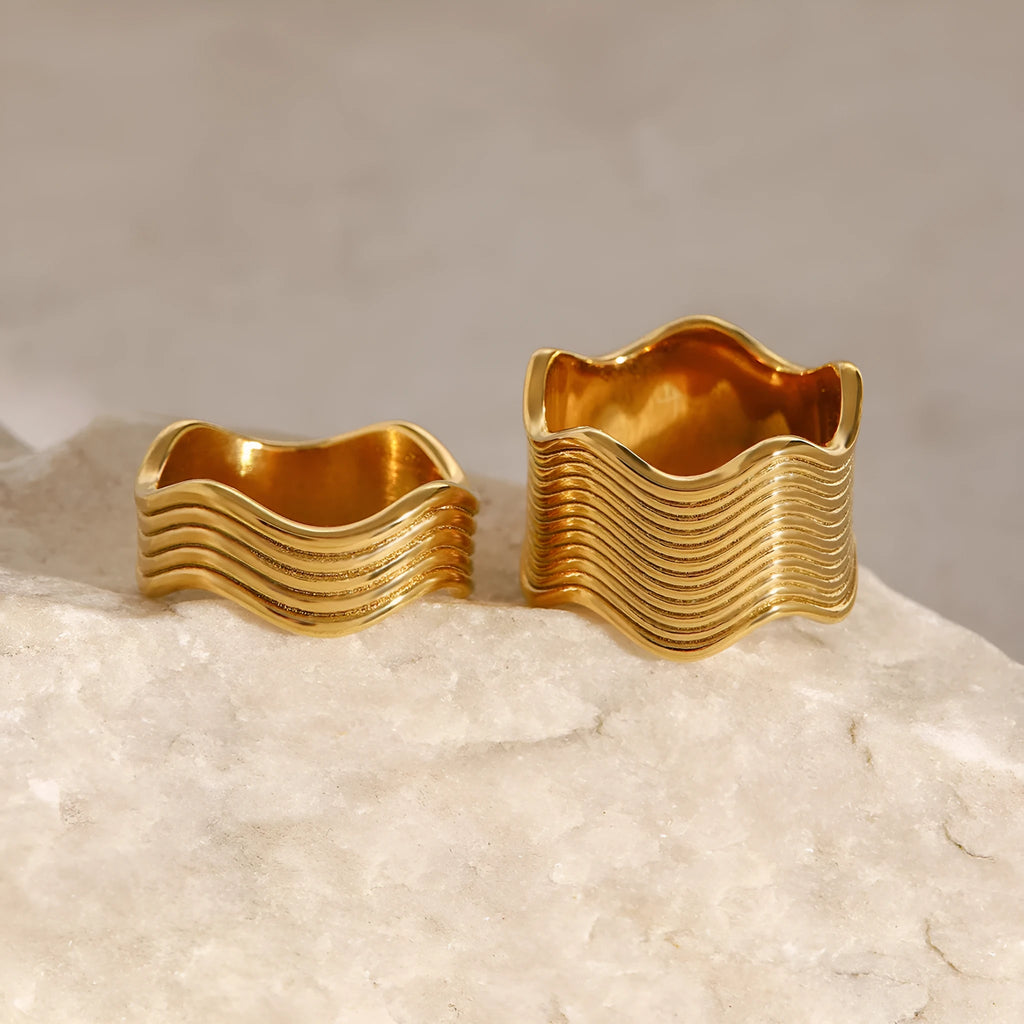 Stainless steel wide band ring with a geometric wave pattern in a metallic finish.