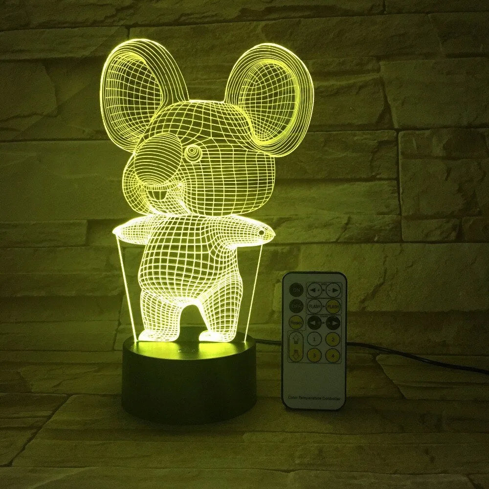 Black koala-shaped LED night light with remote control on a table, showing multi-colour illumination.