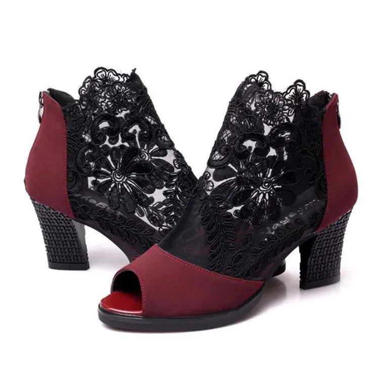 Black lace gladiator sandals with a square high heel and zip closure on a woman's foot.